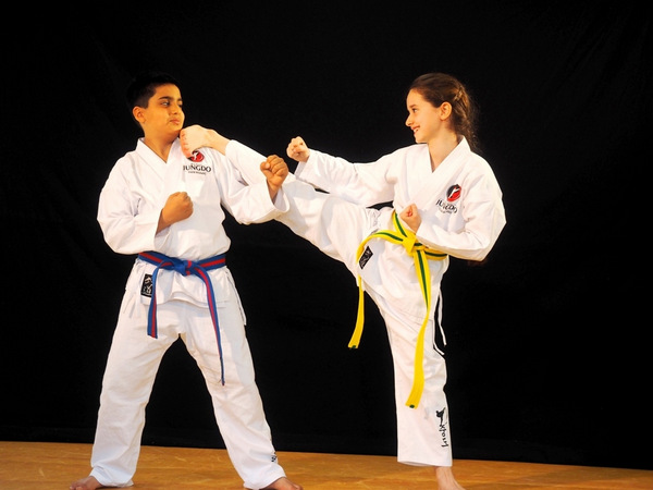 ein mädchen und ein Junge zeigen Kontrolle und Freude am Taekwondo mit Fuss auf Schulter